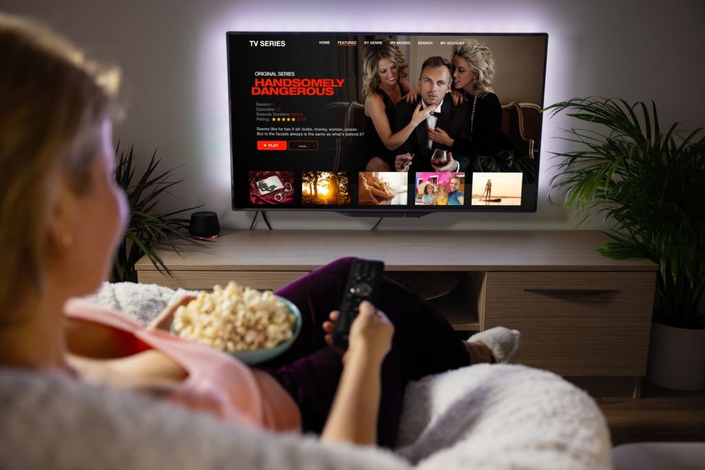 Person using a TV remote to browse a live TV streaming app at home